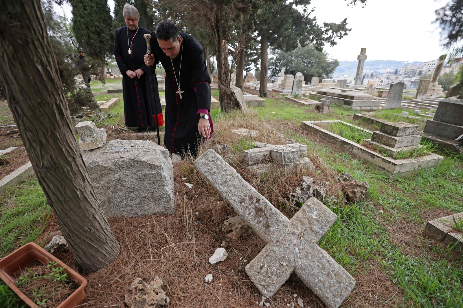 Zeladores do cemitério protestante inspecionam túmulos vandalizados no Monte Sião, fora da Cidade Velha de Jerusalém.  — Foto: AHMAD GHARABLI / AFP