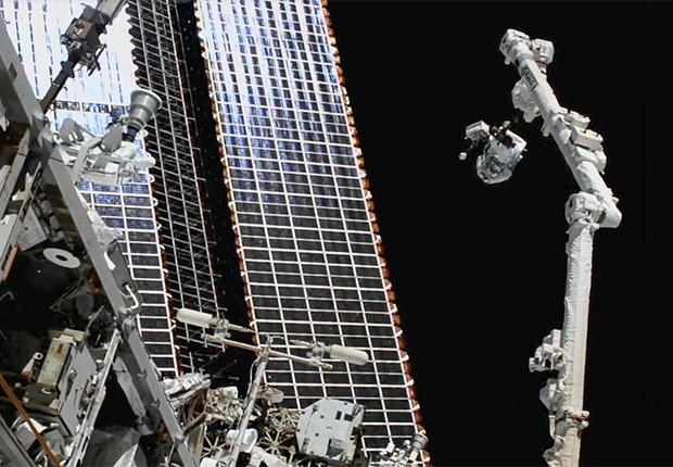 O astronauta Thomas Marshburn escala braço robótico para trocar uma antena da estação (no alto, à direita na foto) (Foto: Reprodução/Nasa)