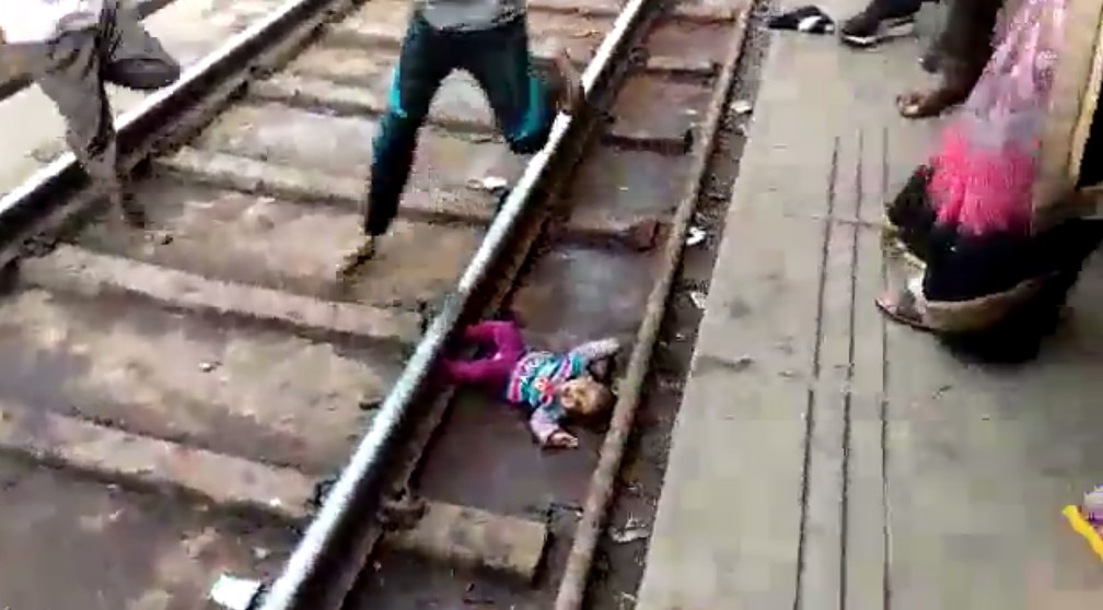 Homem pula em trilhos de trem de estação na Índia para resgatar bebê que caiu — Foto: NNIS / AFP