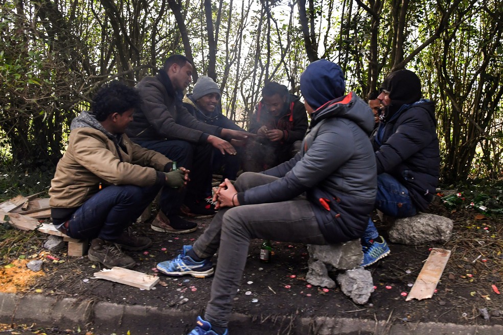 Migrantes ficam em volta de fogueira para se aquecer em Calais, na França (Foto: PHILIPPE HUGUEN / AFP)