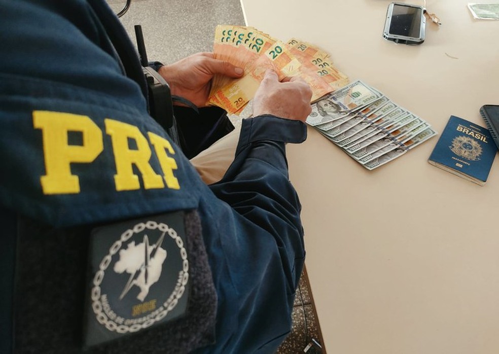Com o suspeito foram apreendidos cédulas de reais e dinheiro — Foto: PRF/Divulgação