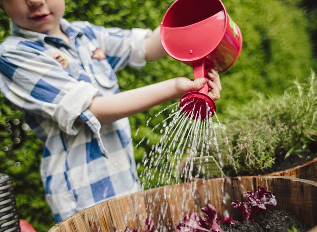 Criança aguando plantas (Foto: Getty Images)