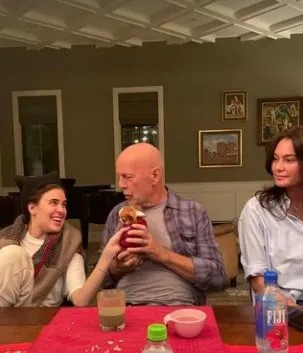 O ator Bruce Willis entre a filha (à esquerda) e a mulher, num jantar em casa: ator segura filhote de cachorro à mesa — Foto: Reprodução/ Instagram