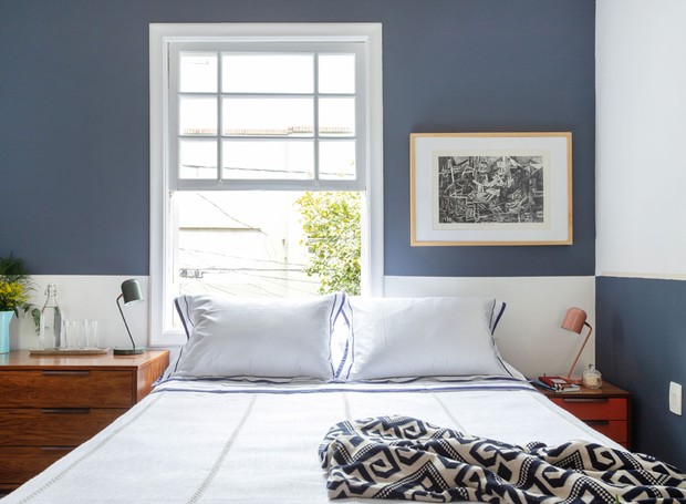 Na parede de cabeceira da cama, a disposição de branco e azul é invertida, valorizando a moldura branca da janela. Mesa de cabeceira Fernando Jaeger. Obras de arte Papel Assinado.   (Foto: Maura Mello/Divulgação)