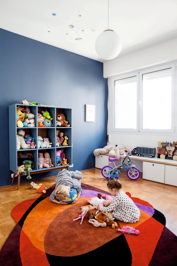 Quarto de brinquedos. Leon e Eva brincam sobre o tapete da Punto e Filo no cômodo que tem uma das paredes pintadas de azul (Foto: Maíra Acayaba / Editora Globo)