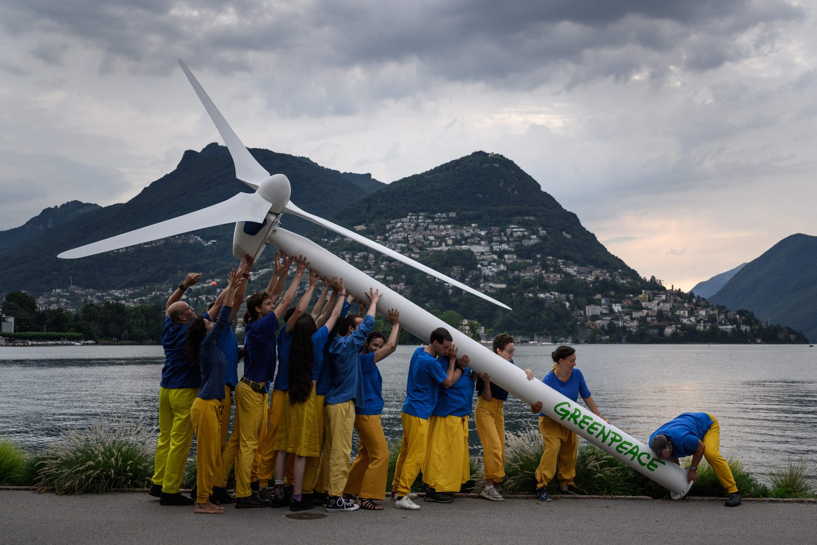 Ativistas do Greenpeace levantam uma turbina eólica na beira do Lago Lugano durante manifestação para pedir reconstrução sustentável da Ucrânia, antes de uma Conferência de Recuperação da Ucrânia de dois dias, em Lugano — Foto: FABRICE COFFRINI / AFP