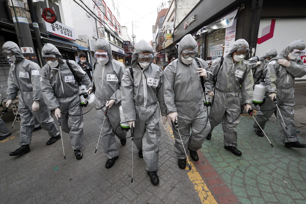 4 de março: Soldados do exército da Coreia do Sul, vestidos com trajes de proteção contra o Covid-19, espalham desinfetante pelas ruas de Seul, na Coreia do Sul. — Foto: Ahn Young-joon/AP