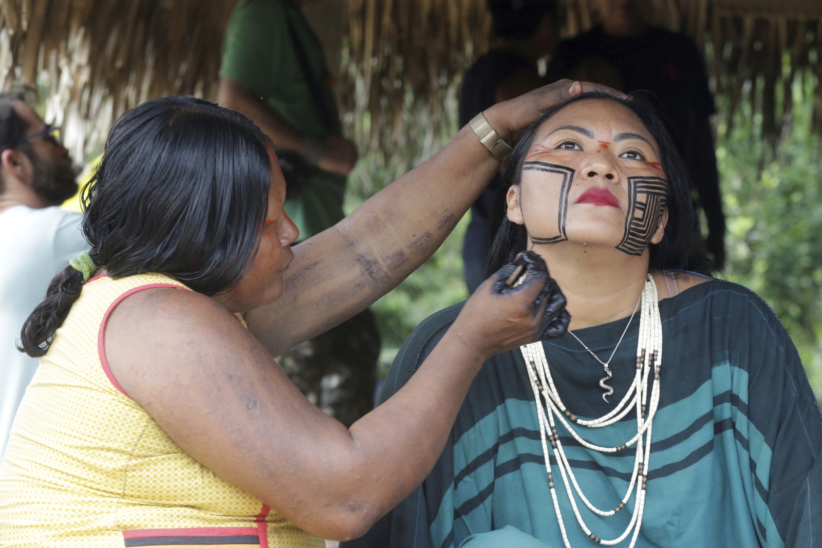 A indígena kayapó Nhãkraxti pinta Elaine Pyãko, mulher do líder ashaninka Francisco Pyãko, durante festa da caiçuma -  Foto: Domingos Peixoto / Agência O Globo