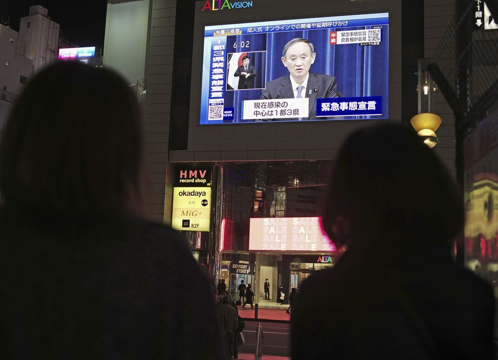 Japoneses assistem a pronunciamento do primeiro-ministro Yoshihide Suga na TV sobre a declaração de emergência na região de Tóquio em 7 de janeiro de 2021 — Foto: Hiro Komae/AP