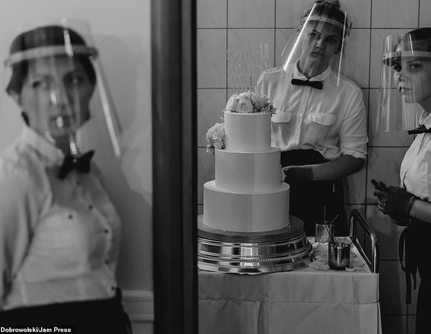 Na Polônia, funcionários esperam para entregar o bolo aos noivos usando escudos de plástico sobre o rosto e luvas (Foto: Mateusz Dobrowolski)