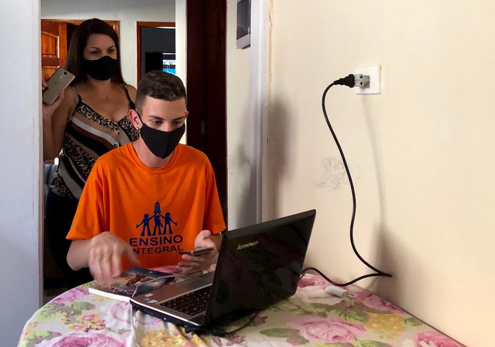 Ryan Piehler Soares criou biblioteca virtual com o computador da tia (atrás dele na foto) — Foto: Arthur Costa/TV Vanguarda