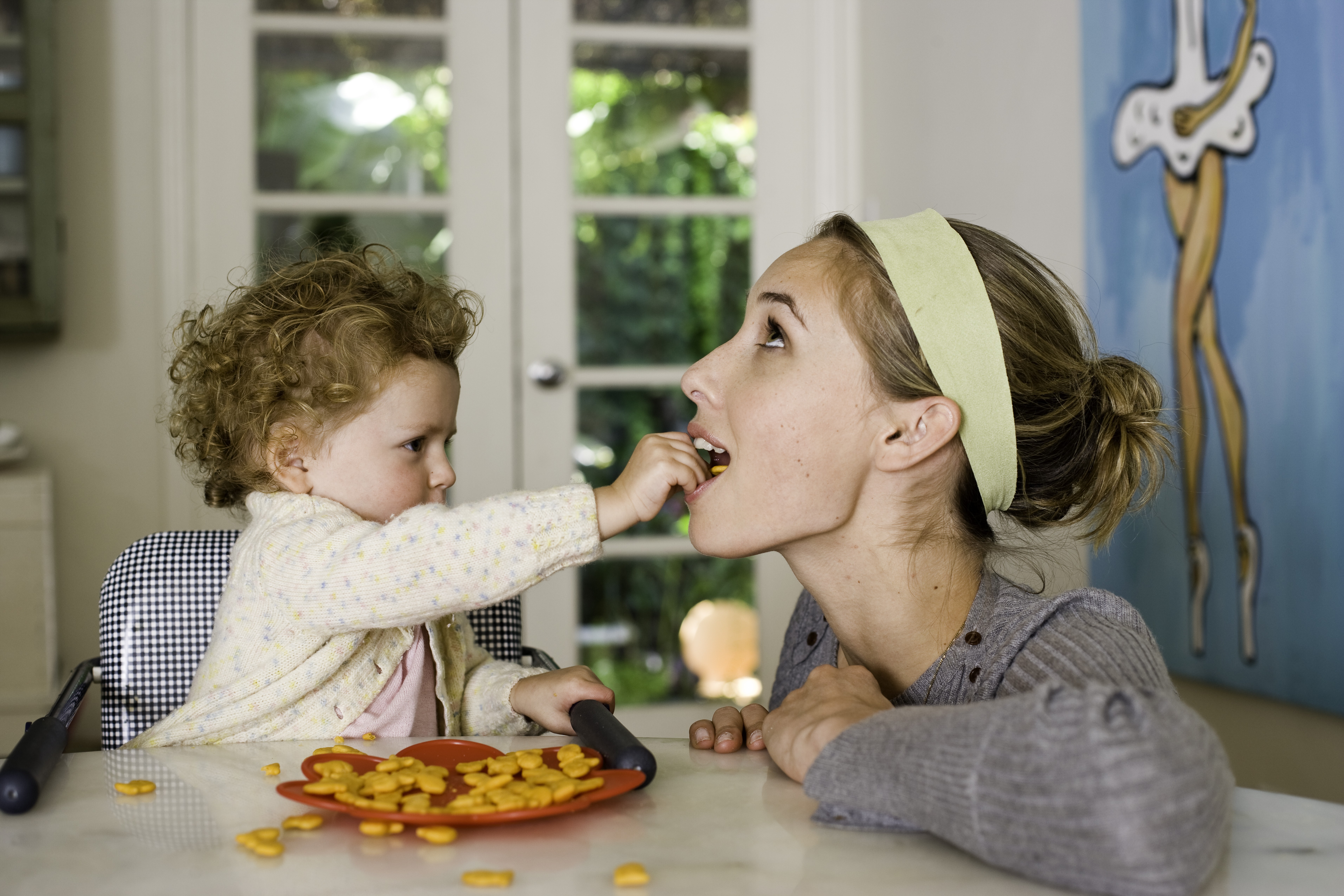 Criança comendo com a mãe (Foto: Getty Images)