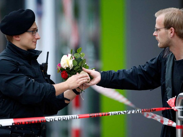 Rapaz oferece flores a um policial para colocá-las em centro comercial (Foto: Michael Dalder / Reuters)