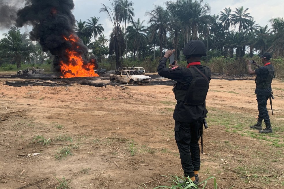 Agentes de segurança fotografam o local da explosão do oleoduto em Emohua, Nigéria, em 3 de março de 2023 — Foto: REUTERS/Tife Owolabi