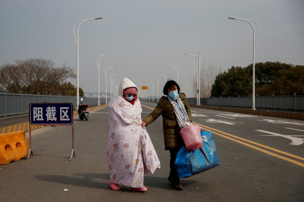 1º de fevereiro - Paciente de leucemia e sua mãe, vindas da província de Hubei, passam pela ponte Jiujiang Yangtze, na China — Foto: Thomas Peter/Reuters