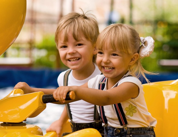 Irmãos brincando em parque de diversão (Foto: Shutterstock)