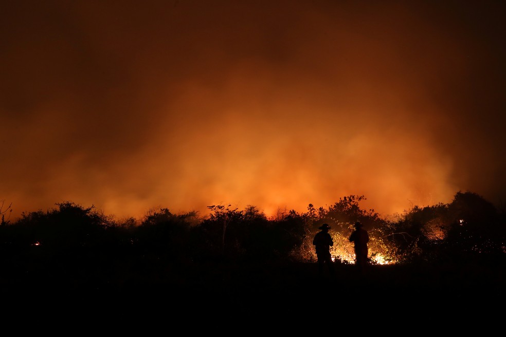 Funcionários de uma fazenda são vistos próximos ao fogo em uma fazenda no Pantanal, em Poconé (MT) — Foto: Amanda Perobelli/Reuters