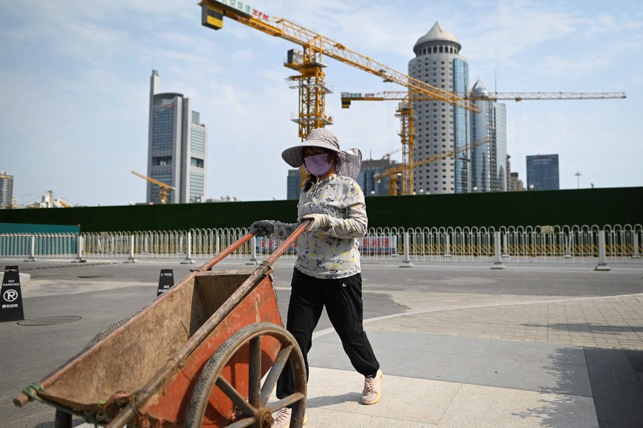 Trabalhador empurra carrinho ao longo de um canteiro de obras no Distrito Comercial Central em Pequim