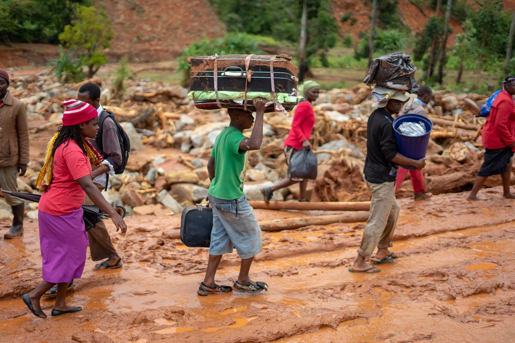 Sobreviventes deixam Ngangu levando seus pertences em malas após a passagem do ciclone Idai em Chimanimani, no Zimbábue — Foto: Zinyange Auntony/AFP