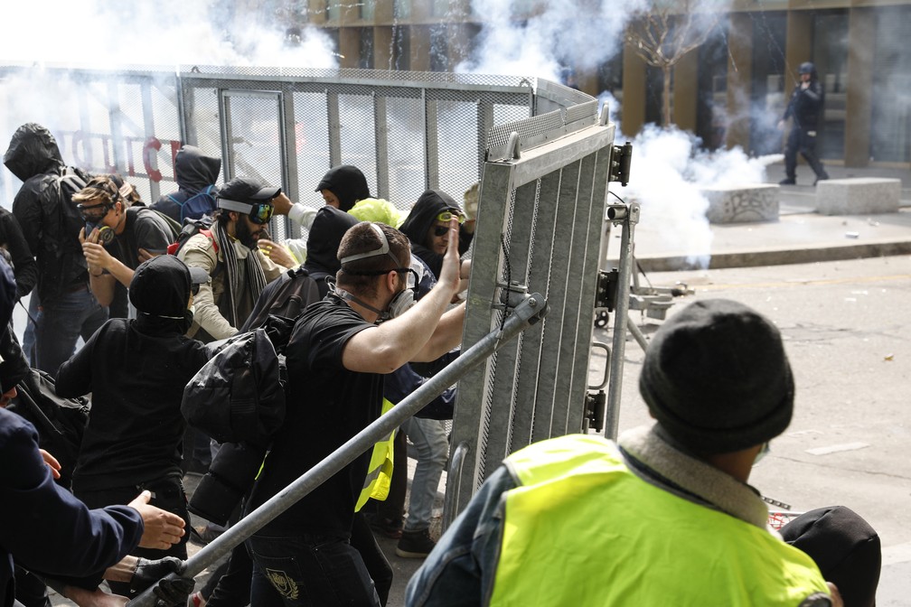 Manifestantes forçam barreiras de contenção durante protestos do Dia do Trabalho em Paris — Foto: Geoffroy van der Hasselt/AFP