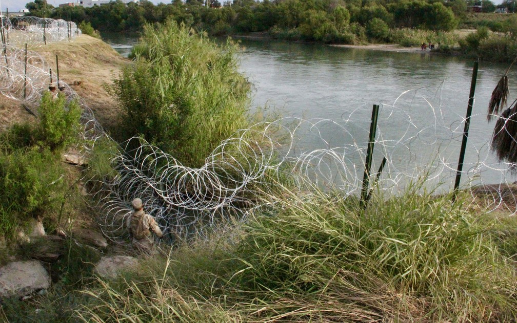 Soldados do 19º Batalhão de Engenharia de Kentucky instalam cercas de arame farpado nas margens do Rio Grande, em Laredo, no Texas, no domingo (18) — Foto: Thomas Watkins/AFP