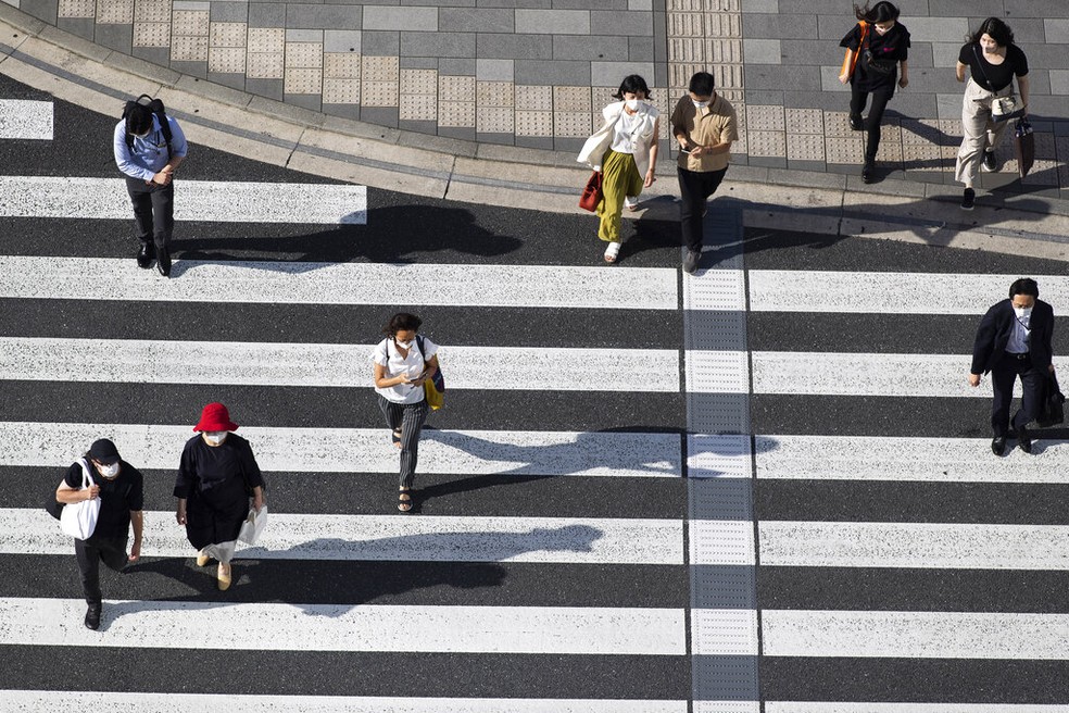 Pessoas cruzam faixa de pedestres em Tóquio, capital do Japão, na quinta (15) — Foto: Hiro Komae/AP Photo