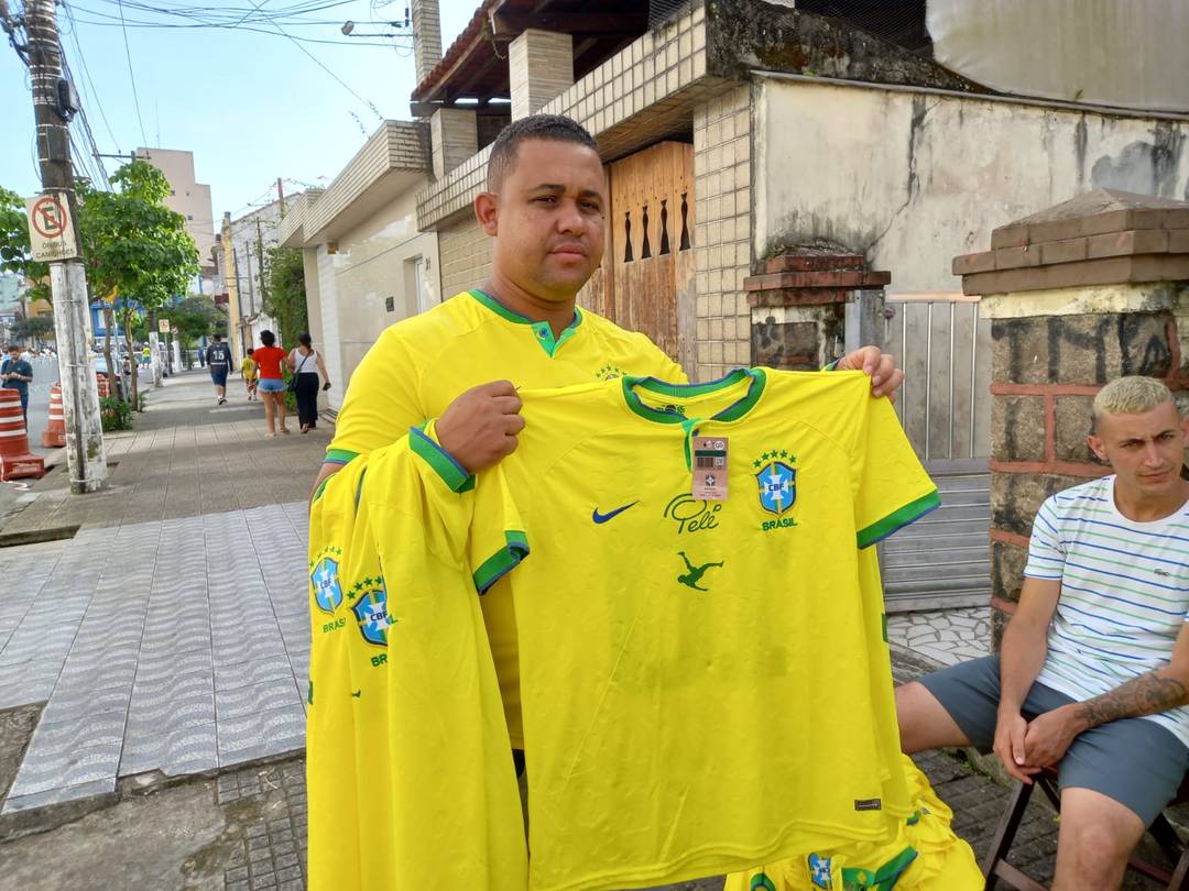 Comerciante Antônio Ferreira viu uma chance de homenagear o Rei vendendo camisas da Seleção nos arredores da Vila Belmiro, em Santos, no litoral de SP, na manhã desta segunda-feira (2).