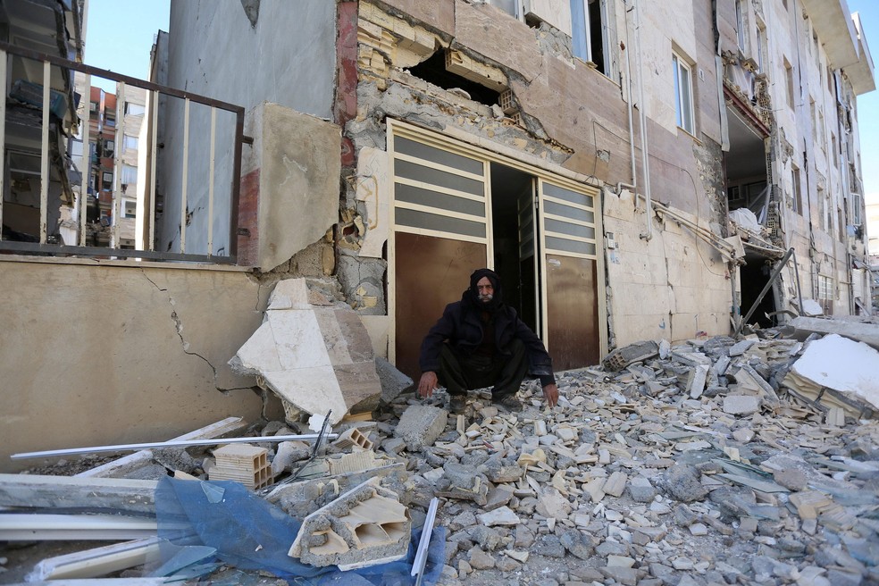 Homem é fotografado sentado sobre destroços, nesta segunda-feira (13), após tremor que atingiu a província iraniana de Kermanshah (Foto: Tasnim News Agency/ Reuters)