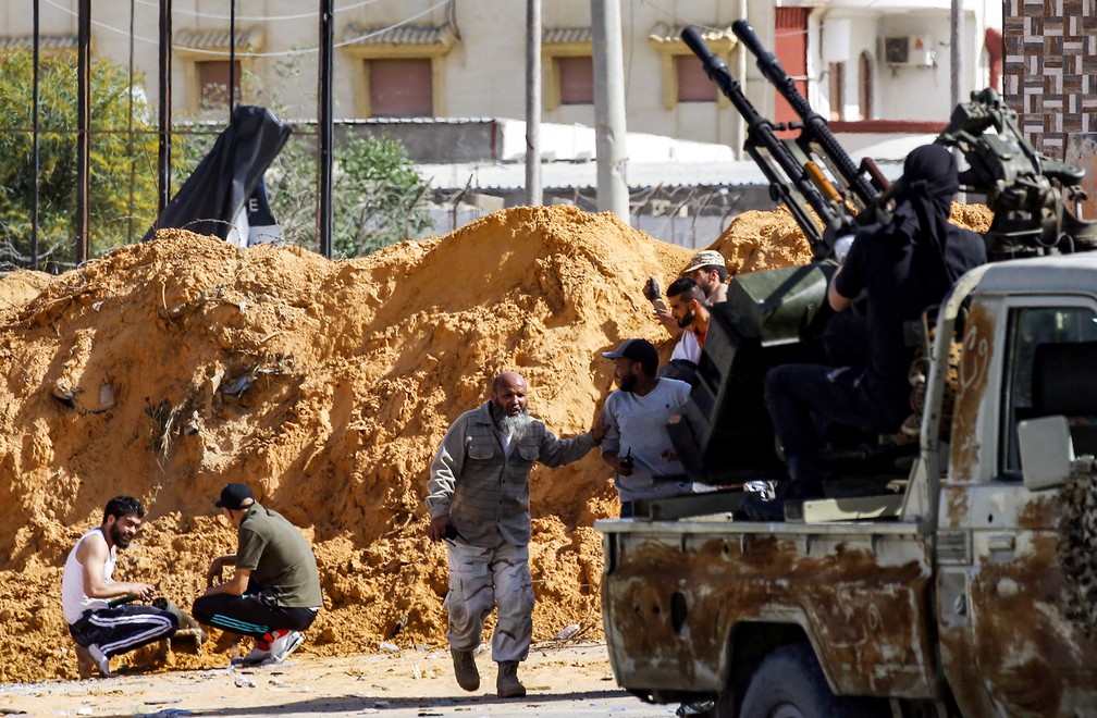 Forças do governo da capital se protegem atrás de barreira de terra em confronto com as forças do leste, em Trípoli, nesta quarta (10). — Foto: Mahmud Turkia/AFP