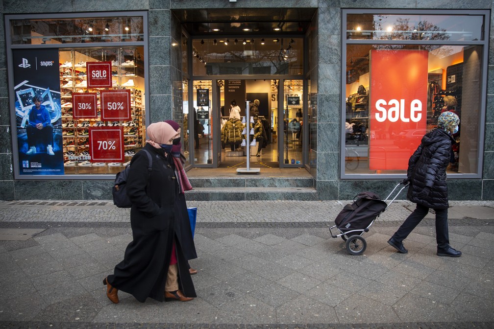 Pedestres com máscara de proteção à Covid passam por loja de sapatos em Berlim, na Alemanha, no dia 11 de dezembro — Foto: Odd Andersen/AFP
