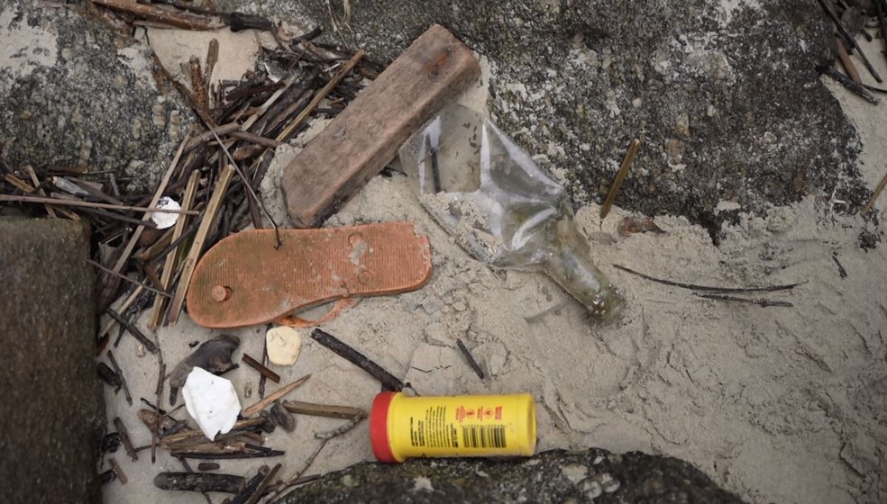 Lixo chega à praia deserta por meio da maré — Foto: RPC