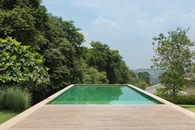 De concreto, a piscina revestida de pastilhas de vidro projeta-se ao longo do declive do terreno e parece flutuar (Foto: Cacá Bratke / Editora Globo)