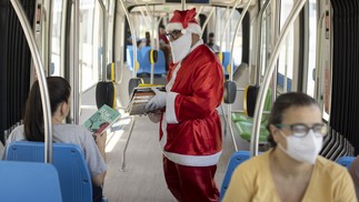 Papai Noel do VLT distribui livros para os passageiros — Foto: Márcia Foletto / Agência O Globo