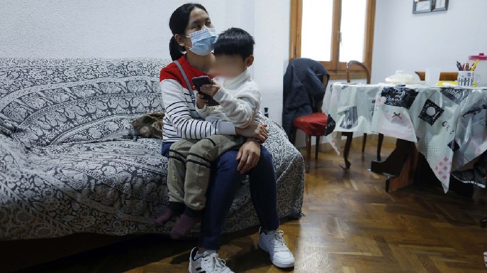 O menino que salvou sua mãe grávida, em Valência, enviando áudios com seu celular, sentado sobre uma amiga da mulher (Foto:   Reprodução: Levante-emv/M. A. MONTESINOS)