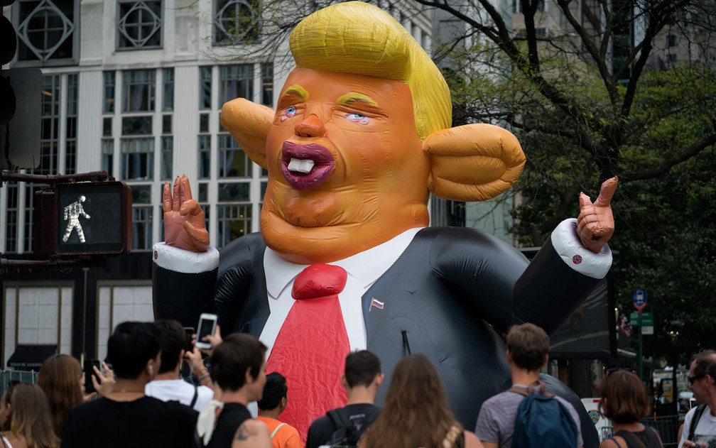 Pessoas fotografam inflável que caracteriza o presidente dos EUA, Donald Trump, como um rato, exposto em frente a Trump Tower, em Nova York, durante protesto na segunda (14) (Foto: AP Photo/Craig Ruttle)