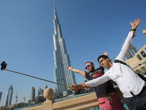 Turistas em Dubai usam bastão de selfie para tirar foto em frente ao arranha-céu Burj Khalifa (Foto: Kamran Jebrelli/AP)