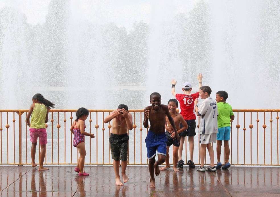 Crianças se divertem brincando com a água espirrada de uma fonte no Parque Battersea, em Londres — Foto: Simon Dawson/Reuters