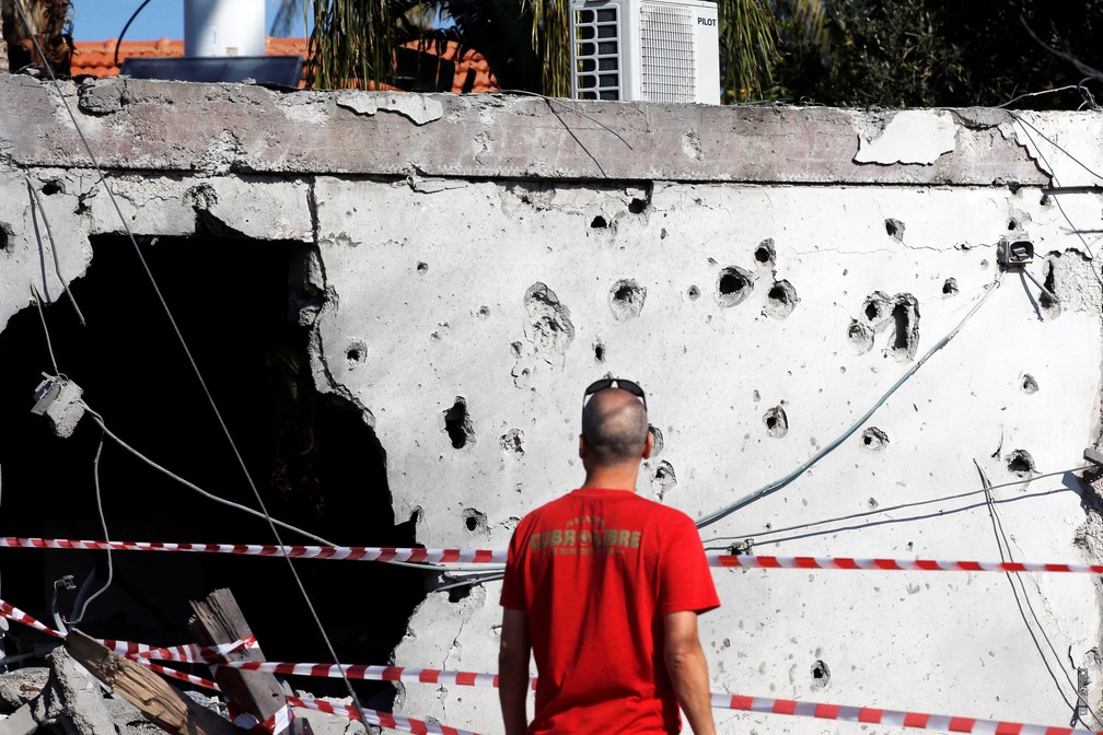 Homem olha nesta terça-feira (13) prédio danificado na cidade israelense de Ashkelon. Ele foi atingido por míssil lançado a partir da Faixa de Gaza  — Foto: Ronen Zvulun/ Reuters