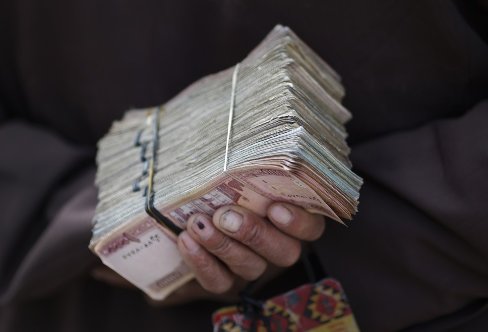 Cambista segura maço de dinheiro em rua no centro de Cabul, capital do Afeganistão, em 2 de abril de 2014 — Foto: Tim Wimborne/Reuters