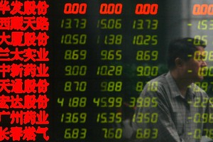 Investidor passa por painel da Bolsa de Valores de Xangai (Foto: China Photos/Getty Images)