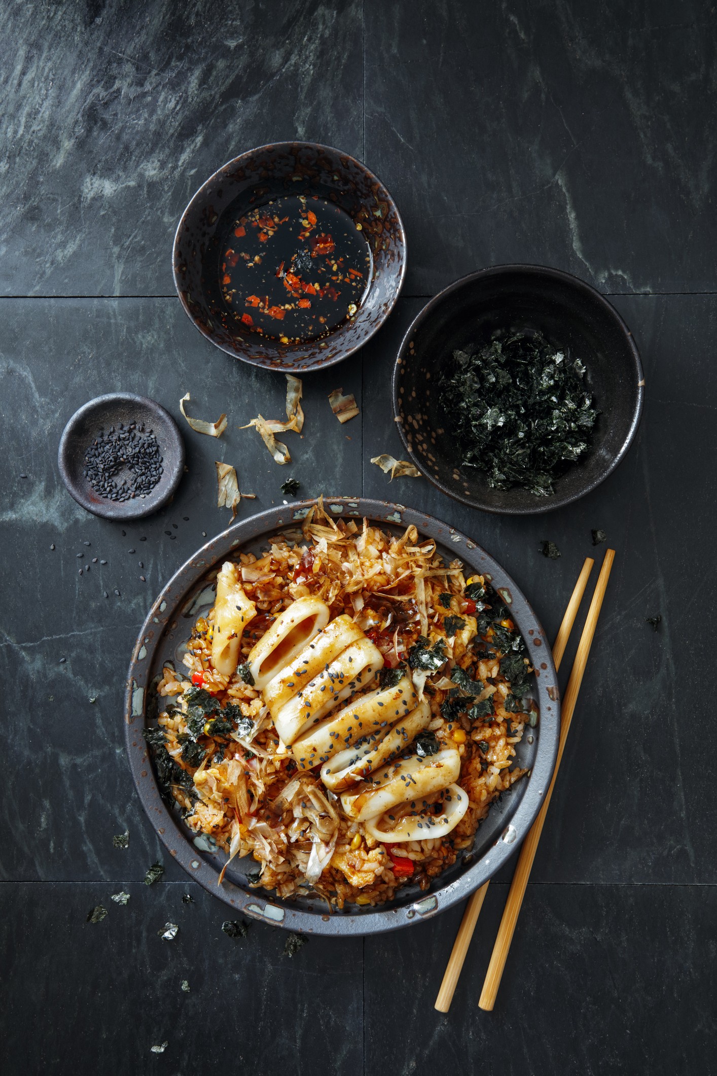 Japanese Grilled Squid with Teriyaki Sauce on Topped Fried Rice Bowl. Flat lay top-down composition on black background. Vertical image with copy space. (Foto: Getty Images)