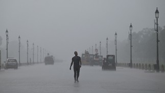 Homem caminha ao longo de Rajpath durante uma chuva de monção em Nova Délhi, Índia  — Foto: MONEY SHARMA / AFP