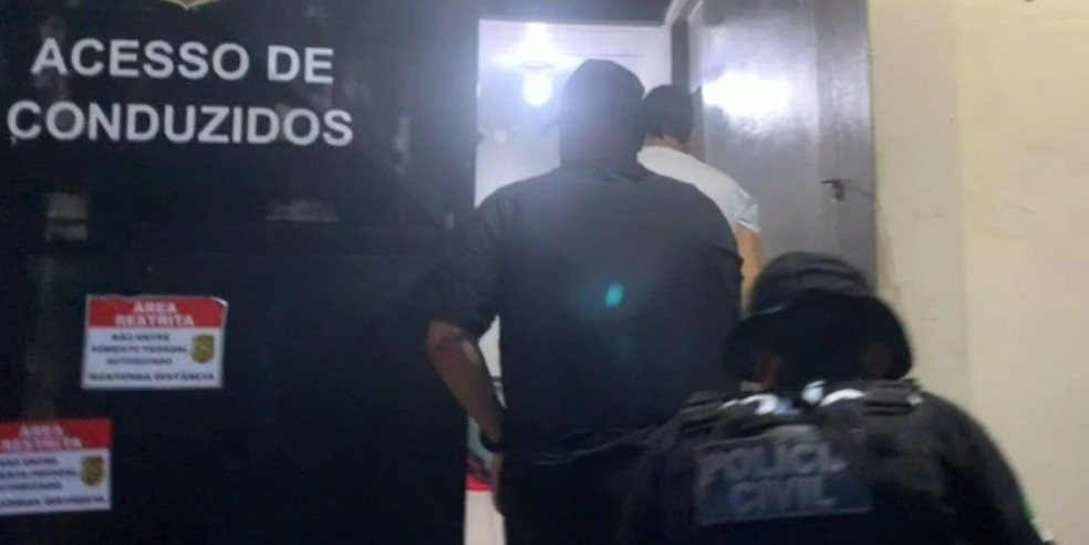 Suspeito preso no RN entra na central de flagrantes da Polícia Civil em Natal acompanhado de policiais — Foto: Polícia Civil do RN/Reprodução