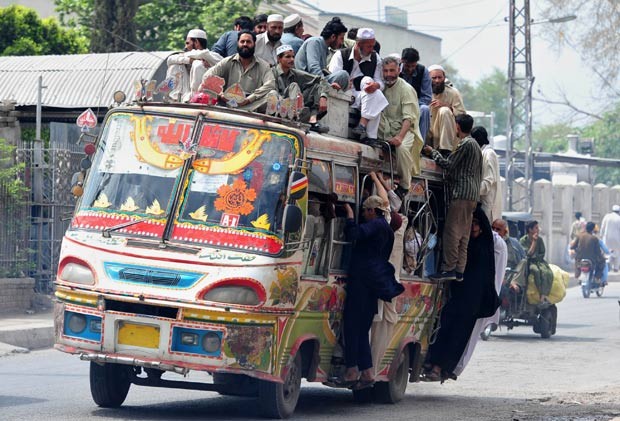 Em 10 de abril de 2012, um ônibus foi flagrado superlotado em Peshawar, no Paquistão. Em cima do teto, viajavam pelo menos 15 pessoas. Outras estavam agarradas às laterais do ônibus. (Foto: A. Majeed/AFP)