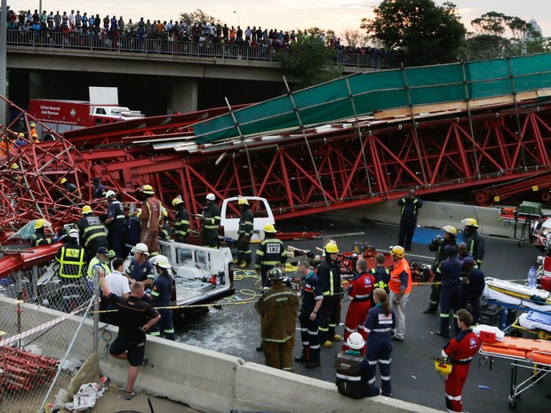 Equipes de emergência e paramédicos trabalham no resgate de um homem ferido após seu carro ser atingido pro andaimes na queda de uma ponte temporária em Joanesburgo, na África do Sul (Foto: Themba Hadebe/AP)