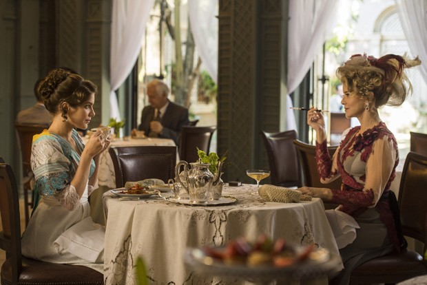 cap 57- cena 008 – Josephine (Christine Fernandes) e Charlotte (Isabela Santoni) ocupam uma mesa. Josephine charmosa com sua piteira e um copo de bebida. Charlotte com um chá. (Foto: Estúdio Globo/Divulgação)