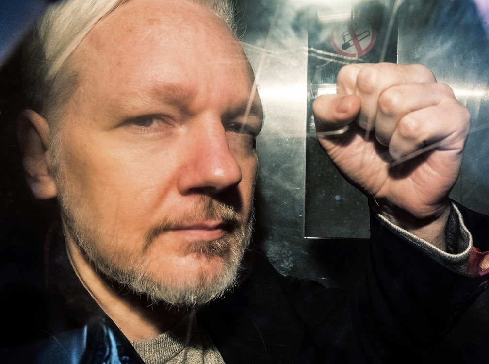 1º de maio: Fundador do Wikileaks, Julian Assange, mostra o punho em riste da janela de uma van ao chegar a um tribunal em Londres, antes de ser condenado a 50 semanas na prisão por não respeitar as condições de sua condicional em 2012, quando se refugiou na Embaixada do Equador para evitar a extradição para a Suécia — Foto: Daniel Leal-Olivas/AFP