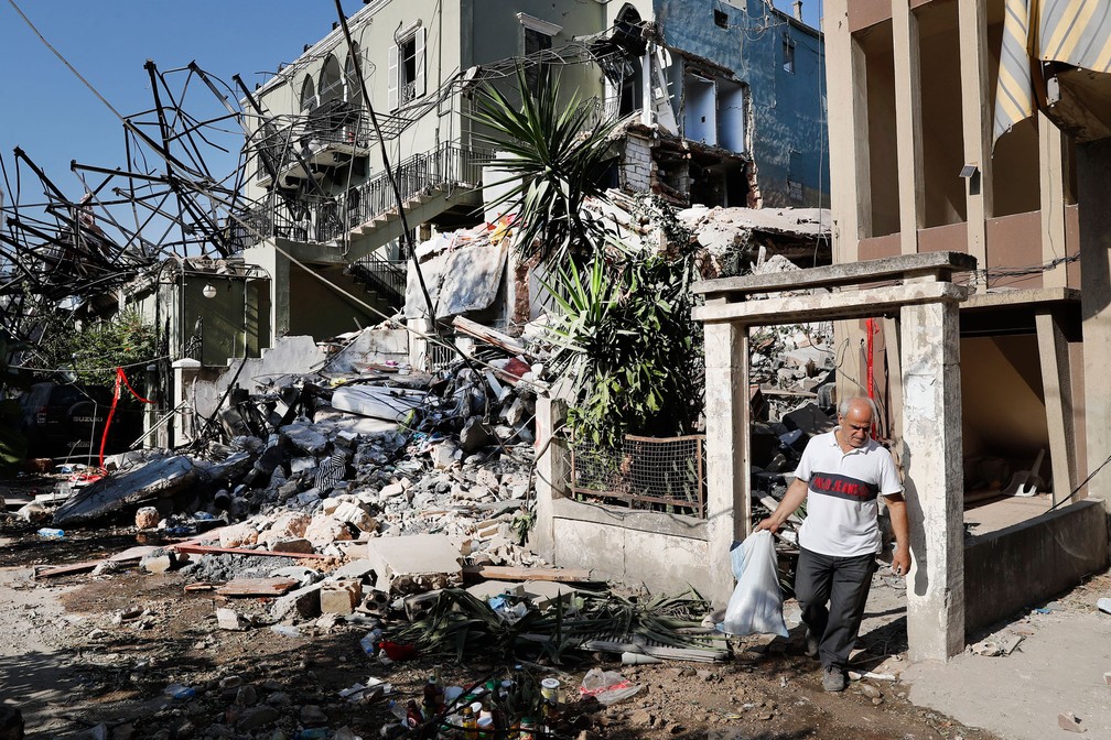 Homem carrega nesta quinta-feira (6) seus pertences ao sair de sua casa destruída por explosão no porto de Beirute, no Líbano  — Foto: Hussein Malla/AP