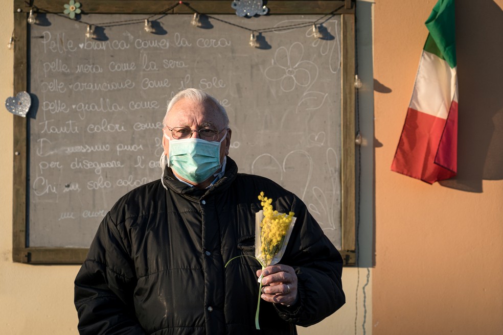 Homem usando máscara protetora contra o Covid-19 em San Fiorano, na Lombardia, segura um buquê de flores. A região, no norte da Itália, é a mais afetada pelo novo coronavírus no país.  — Foto: Marzio Toniolo/via Reuters