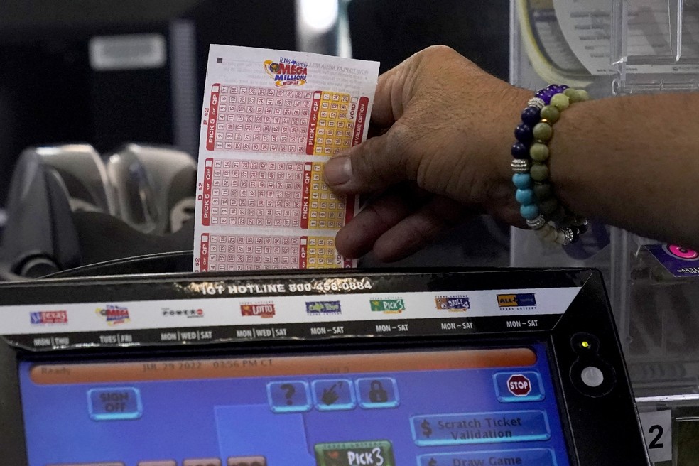 Funcionário de loja de conveniência insere a bilhete da Mega Millions de cliente em máquina no Texas — Foto: AP Photo/Tony Gutierrez